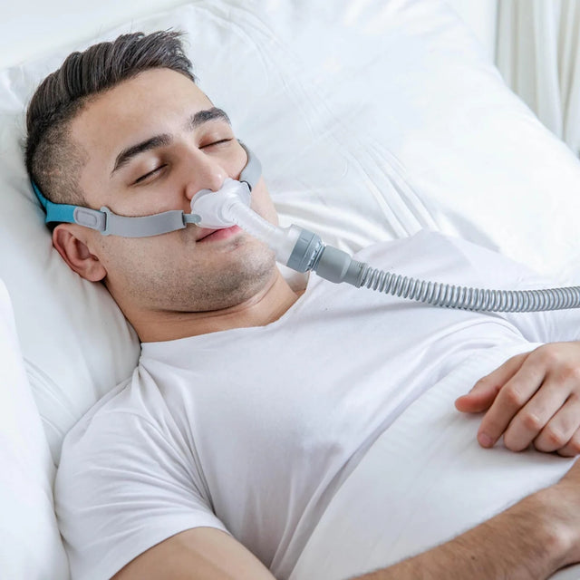 Man wearing a BMC P2 Nasal Pillow CPAP Mask while sleeping in bed