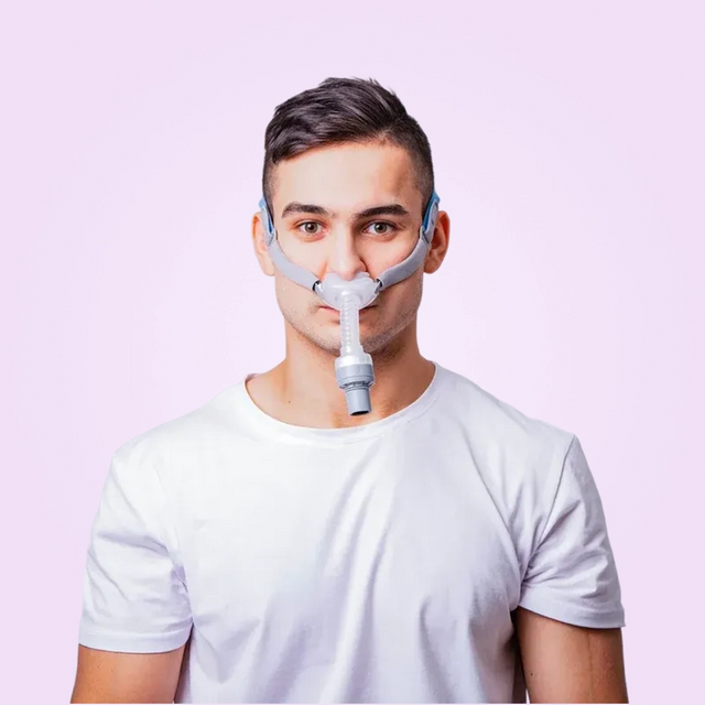 Man wearing a BMC P2H Nasal Pillow CPAP Mask against a pink background