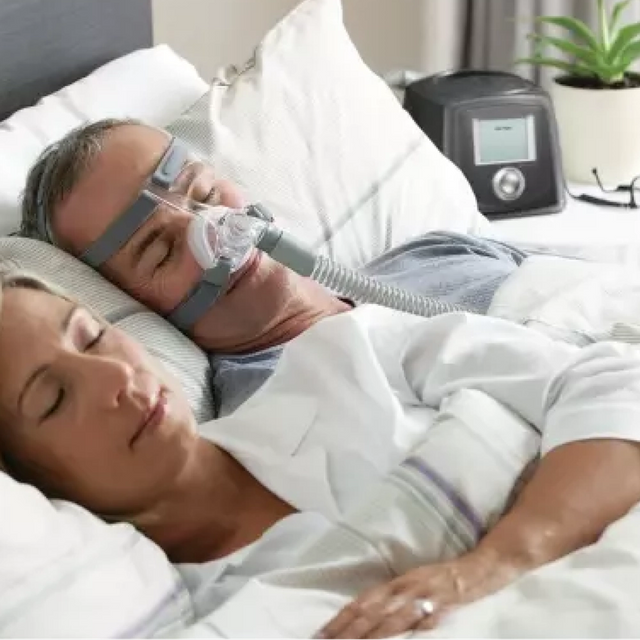 Couple sleeping in bed with the man using Fisher & Paykel Eson Nasal CPAP Mask