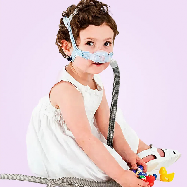 Child wearing a ResMed Pixi Pediatric CPAP Mask with a purple background