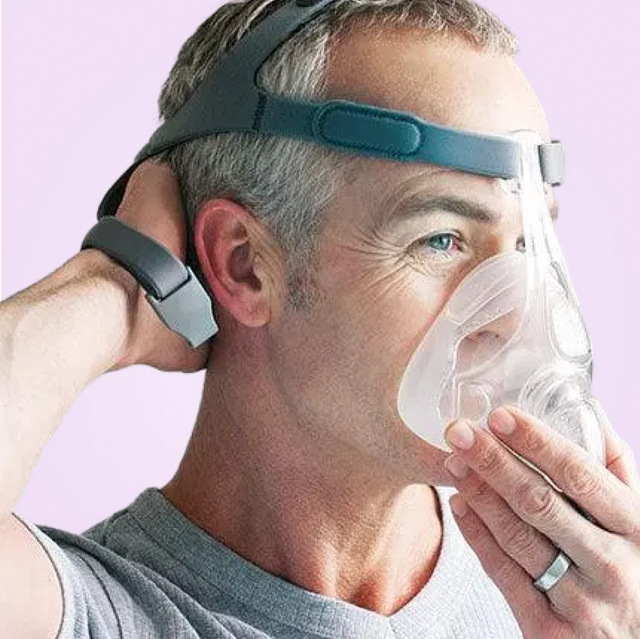 Man adjusting a Fisher & Paykel Simplus Full Face CPAP Mask on his head against a light purple background