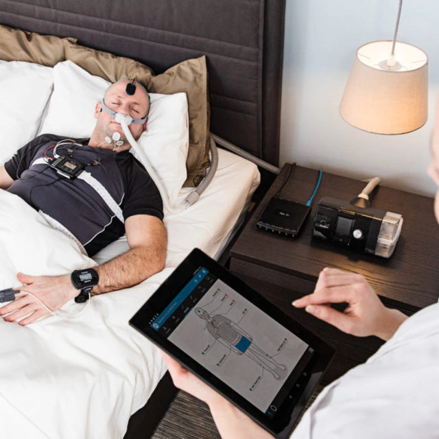 Sleep specialist taking notes of a sleep study on a man with NOX A1 polysomnography (PSG) system