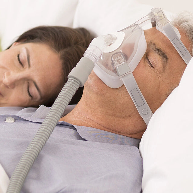 Person wearing a Löwenstein JOYCEone Full Face CPAP Mask with a hose, sleeping peacefully.