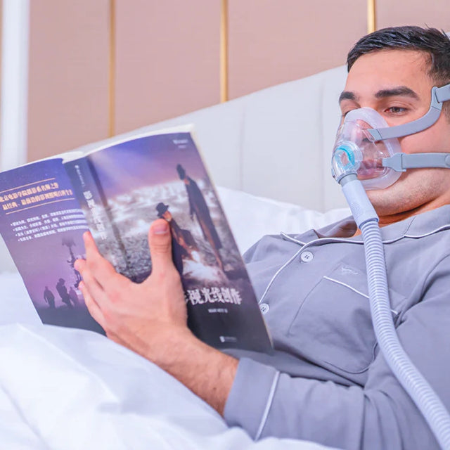 Man using a BMC F5A Full Face CPAP Mask while reading a book in bed