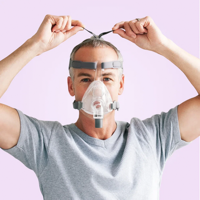 Person wearing a Fisher & Paykel Simplus Full Face CPAP Mask against a light purple background