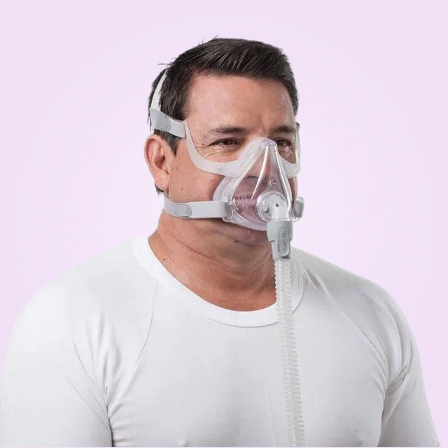 Man wearing a ResMed AirFit™ F10 Full Face Mask against a light purple background