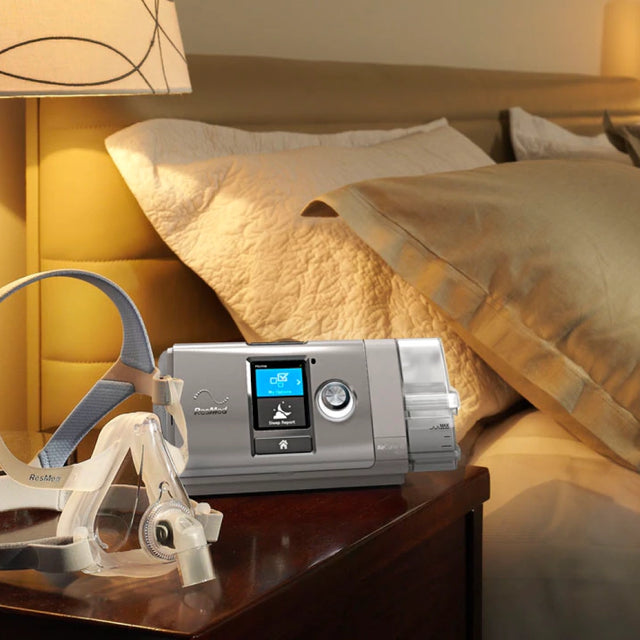 AirCurve 10 CS PaceWave Adaptive Servo-Ventilator with Humidifier next to a ResMed Quattro Air Full Face CPAP mask on a nightstand