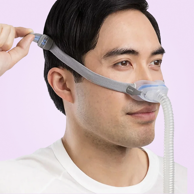 Man wearing a ResMed AirFit N30 Nasal CPAP Mask with a pink background