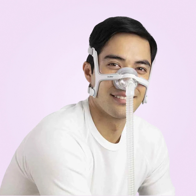 Man wearing a ResMed AirTouch N20 Nasal CPAP Mask on a pink background