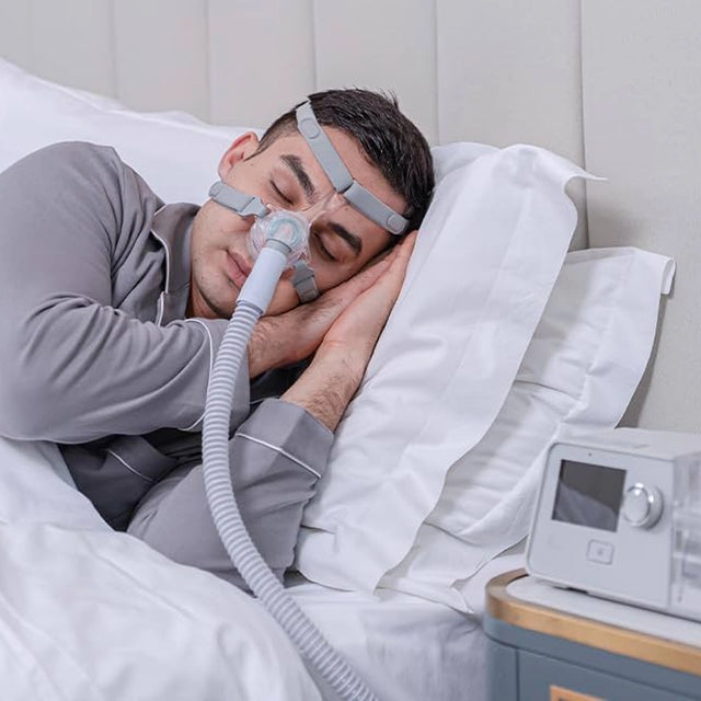 Man using a BMC N5 Nasal CPAP Mask to sleep with a device on his face and hose connected.