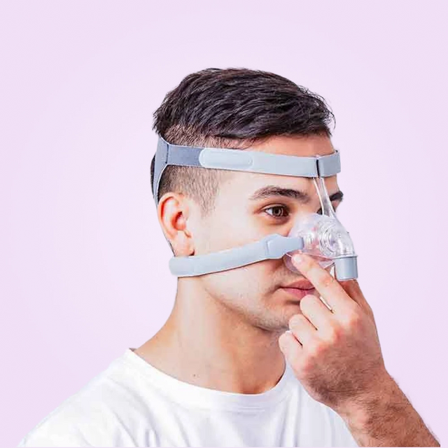 Person adjusting a BMC N5 Nasal CPAP Mask on a pink background