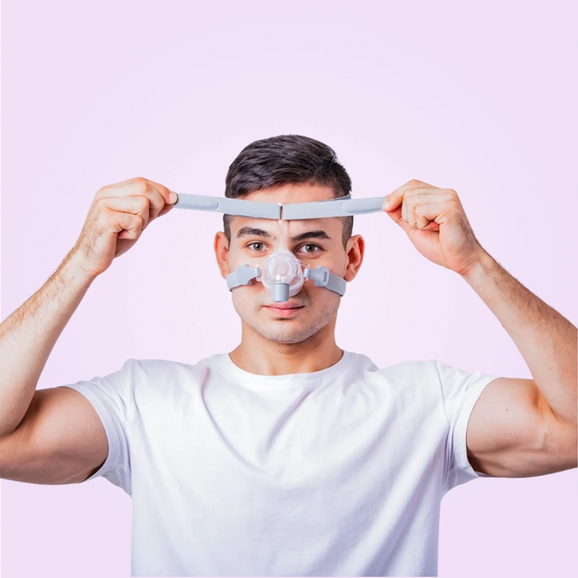 Person wearing a nasal BMC N5 Nasal CPAP Mask device against a pink background