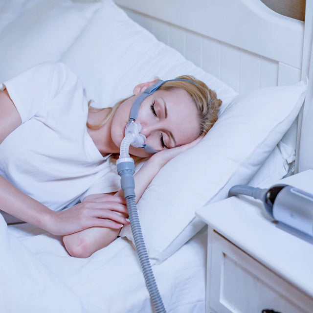 Woman using a BMC P2 Nasal Pillow CPAP Mask while sleeping in a bedroom setting.