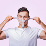 Man adjusting a BMC P2H Nasal Pillow CPAP Mask against a pink background
