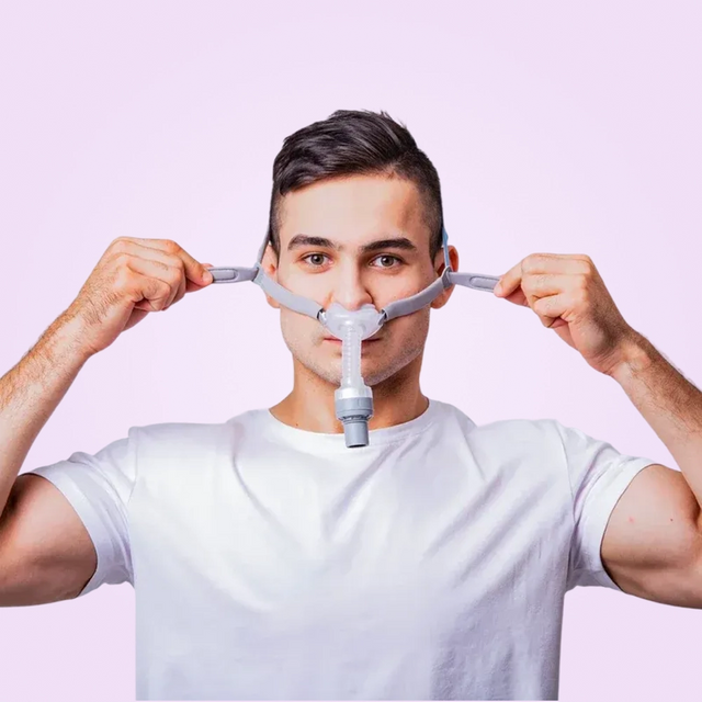 Man adjusting a BMC P2H Nasal Pillow CPAP Mask against a pink background