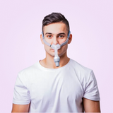 Man wearing a BMC P2H Nasal Pillow CPAP Mask against a pink background