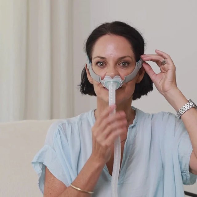 Woman using a BMC P6 Nasal Pillows Mask with a plain background