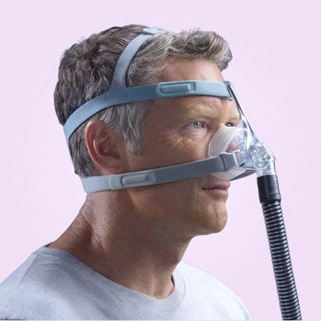 Side view of a man wearing a Fisher & Paykel Eson 2 Nasal CPAP Mask with a pink background