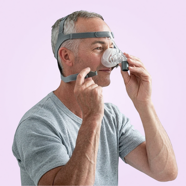 Man using a Fisher & Paykel Eson Nasal CPAP Mask on a pink background