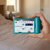 Hand holding SOMNOscreen™ Plus polysomnography (PSG) system in a bedroom setting