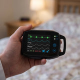 Hand holding SOMNOtouch™ RESP - wrist-worn polygraph in a bedroom setting