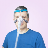 Man wearing a blue Löwenstein Cara Nasal CPAP Mask on a pink background