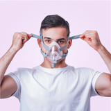 Person adjusting his BMC F5A Full Face CPAP Mask against a pink background