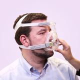 Man adjusting his Löwenstein JOYCEone Full Face CPAP Mask on a pink background