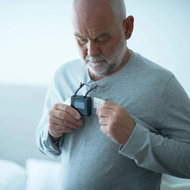 Man attaching NOX T3s home sleep test system on his pyjama