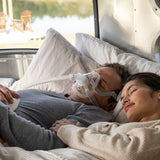 Man wearing a ResMed AirFit™ F20 Full-Face CPAP Mask, lying in bed with a woman next to him