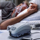 Man sleeping with a CPAP mask on and using Transcend Auto Travel CPAP Machine
