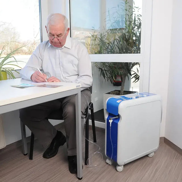 Man sitting at a desk with a Krober 4.0 Oxygen Concentrator next to him