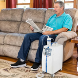 Man sitting on a couch with a KROBER AEROPLUS E 5l/min Oxygen Concentrator next to him