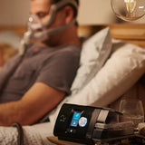 A man using ResMed AirSense 10 Autoset CPAP machine with humidifier