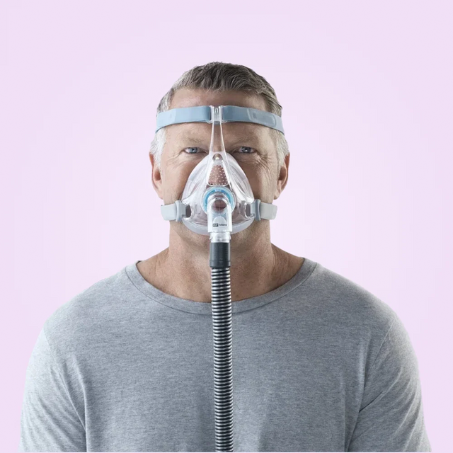 Man wearing a Fisher & Paykel Vitera Full Face CPAP Mask on a pink background