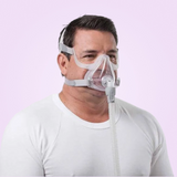 Man wearing a ResMed AirFit™ F10 Full Face Mask against a light purple background