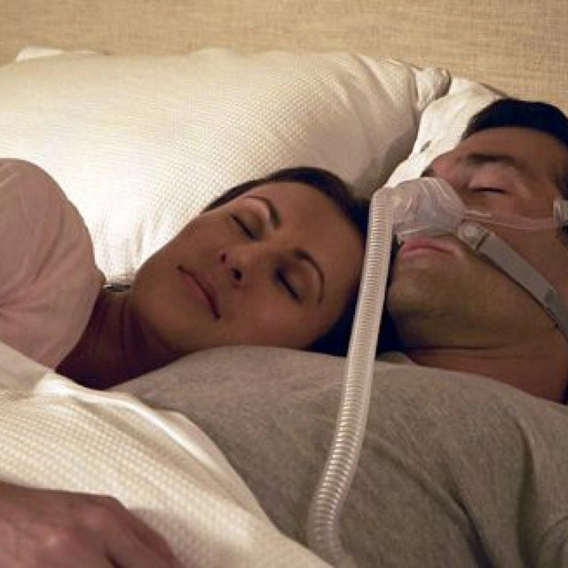 Man using a ResMed AirFit N10 Nasal CPAP Mask while sleeping next to a woman.
