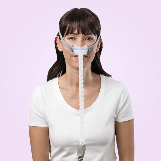 Woman wearing a ResMed AirFit N30 Nasal CPAP Mask on a pink background