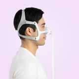 Person wearing a ResMed AirTouch N20 Nasal CPAP Mask with a hose on a light purple background