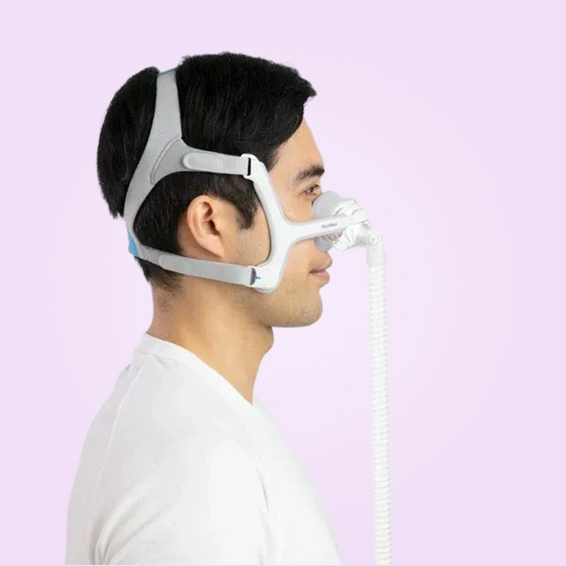 Person wearing a ResMed AirTouch N20 Nasal CPAP Mask with a hose on a light purple background