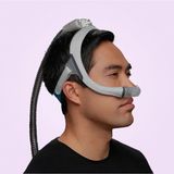 Person wearing a ResMed AirTouch N30i Nasal CPAP Mask on a light purple background