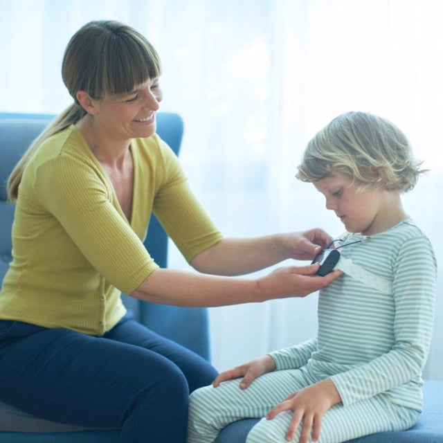 Woman attaching NOX T3s home sleep test system on a little boy's pyjama