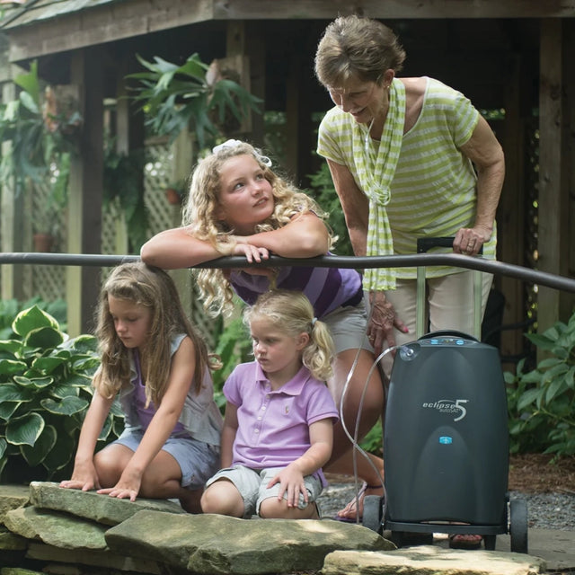 Woman carrying SeQual Eclipse 5 portable oxygen concentrator on a walk with her granddaughters