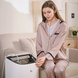 Woman in pajamas using an BMC Oxygen Concentrator 5 LPM in a living room.