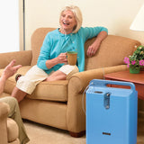 Woman sitting on a couch with a  Philips EverFlo Home Oxygen concentrator system and cup in a home setting